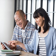 Mature Japanese businessman looking at digital tablet. Asian man and woman looking at digital tablet.