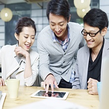 a team of young asian entrepreneurs discussing business in office using tablet computer.