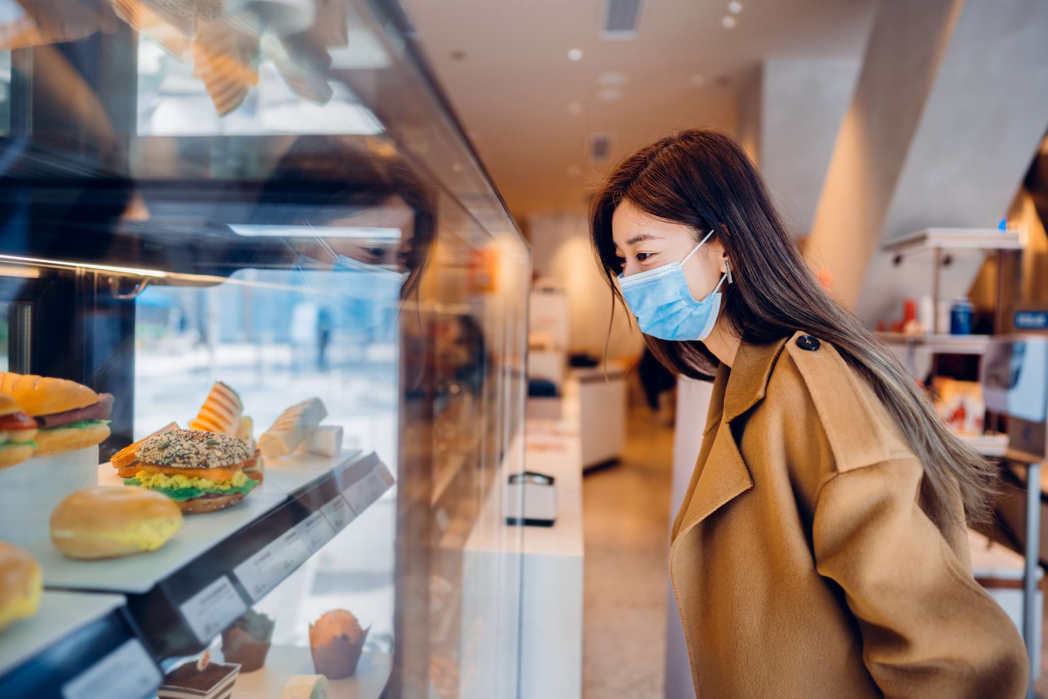 girl with a mask staring at dessert in a cafe